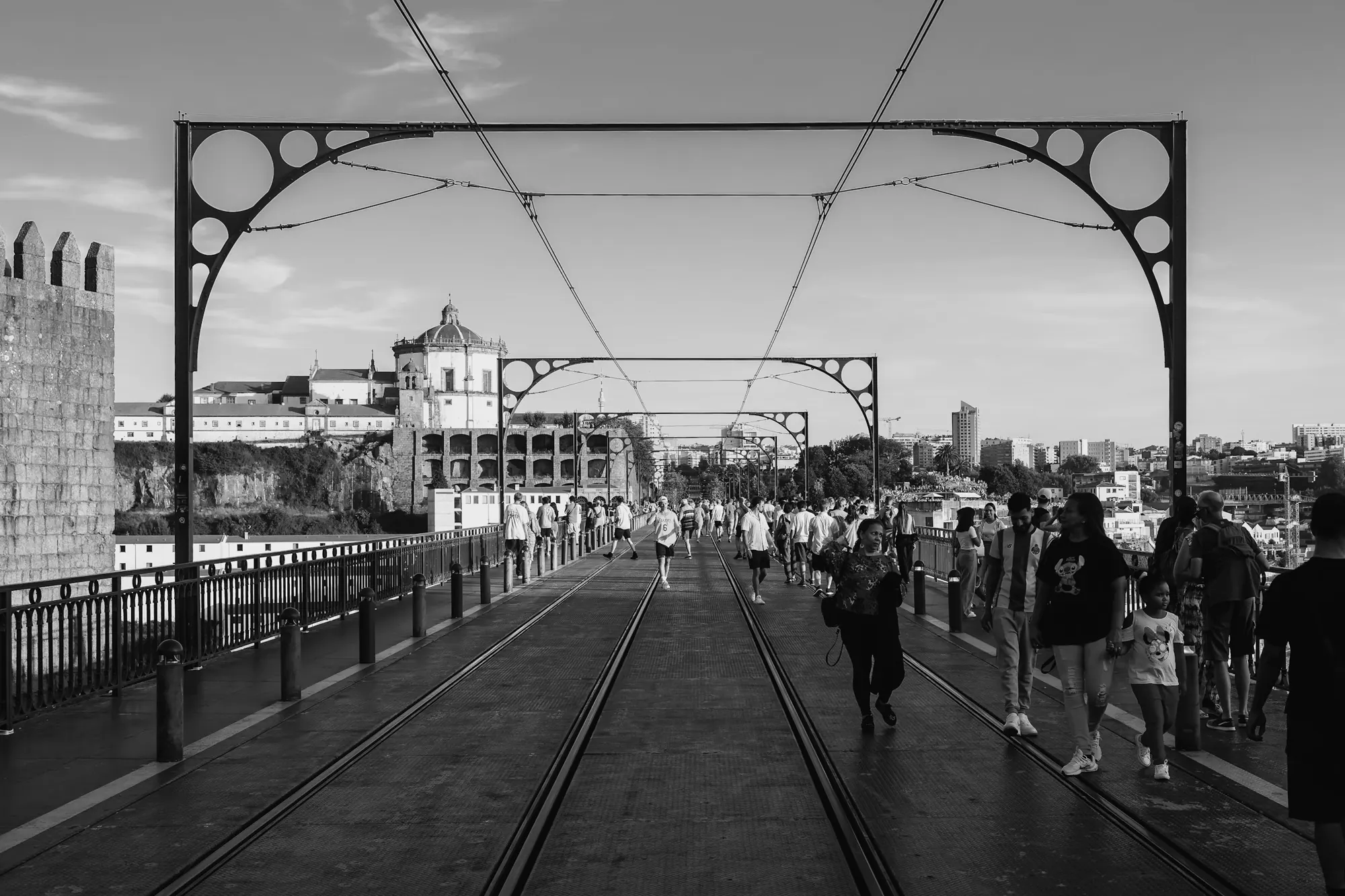 People walking across a bridge between iron arches. Photo by Jordan Ryskamp.
